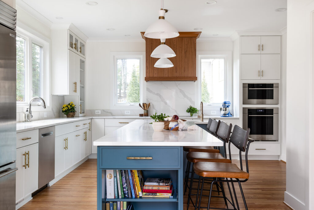 Overall view of bright open kitchen remodel in Fairfax VA featuring Showplace frameless cherry cabinetry, Calacatta Idillio quartz countertops, large seating island, and stainless Wolf and Sub-Zero appliances designed for modern family living and entertaining.